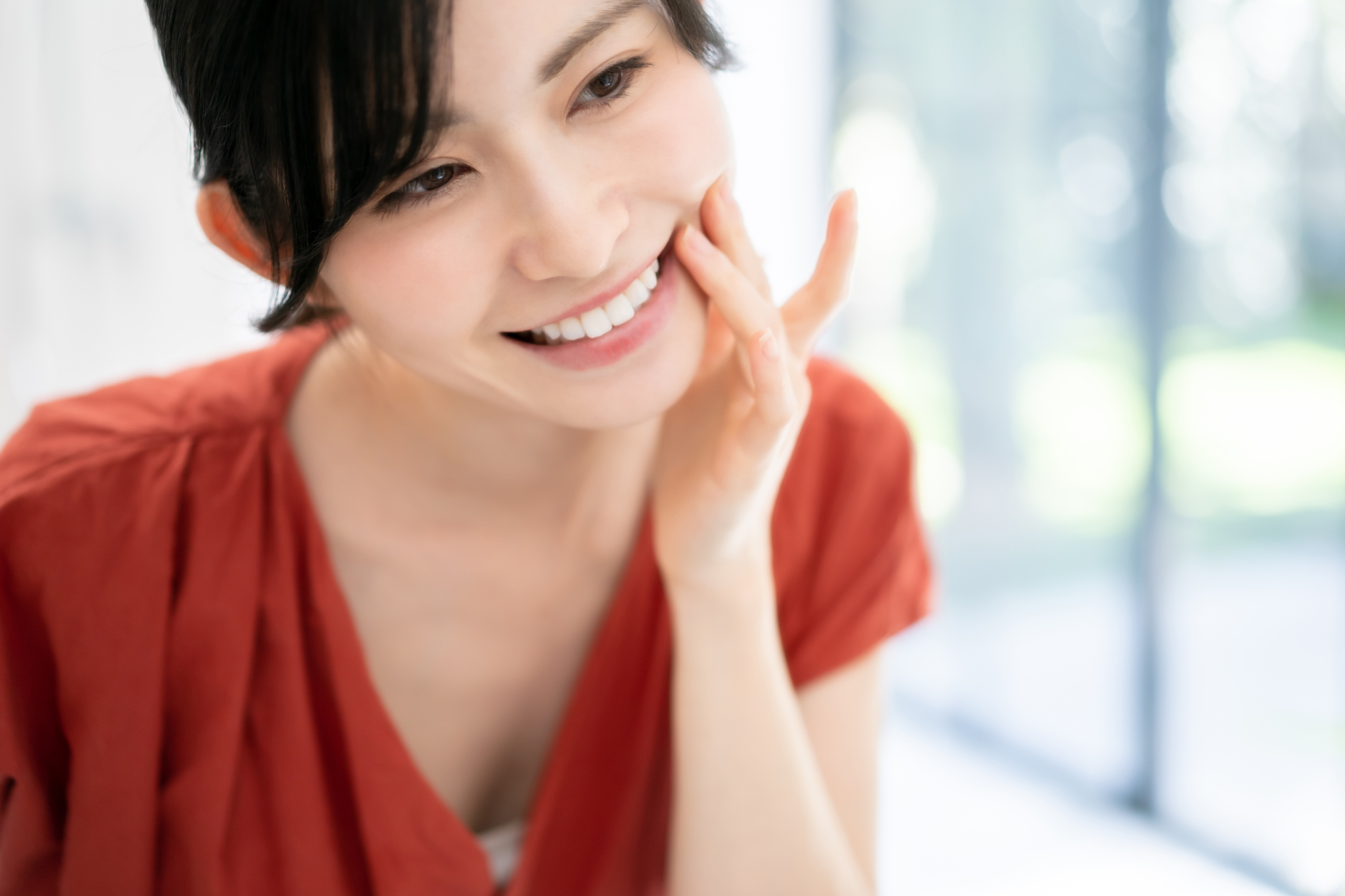インプラント治療で綺麗になった前歯を鏡で確認する女性